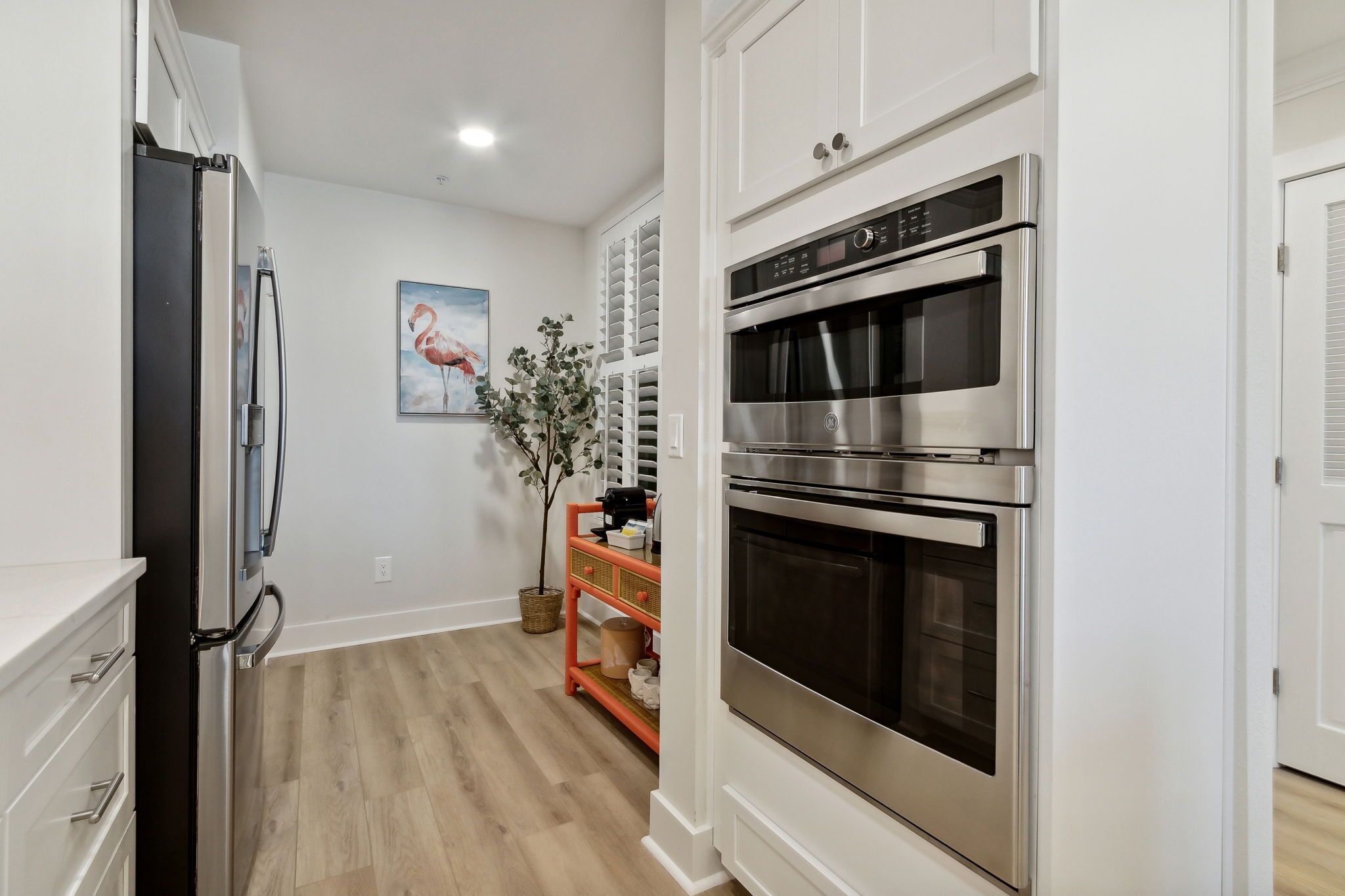 A kitchen with white cabinetry, a stainless steel oven, and a black refrigerator.