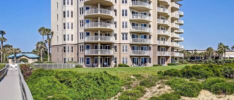 Un hôtel à plusieurs étages doté de balcons, d’une entrée couverte et d’une plage de sable en premier plan.