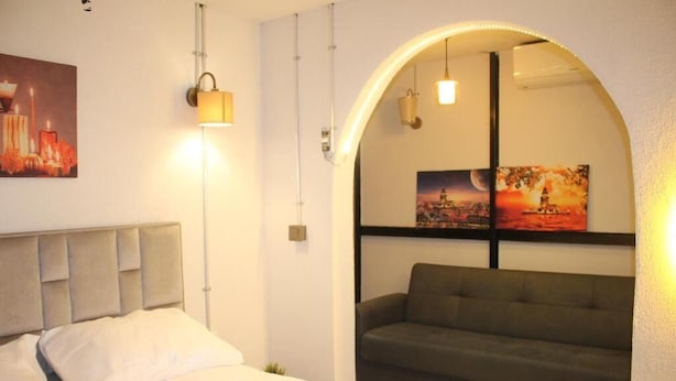 A bedroom with a bed, a sofa, and a wall-mounted lamp. - Ambar Hotel (Istanbul)