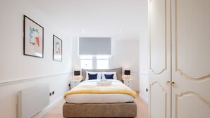 A bedroom with a bed, bedside tables, a radiator, and a wardrobe.