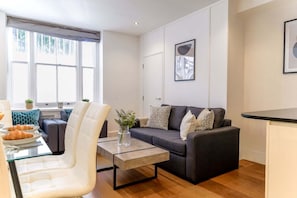 Un salon moderne avec un canapé, une table basse et un coin repas doté d’une table en verre.