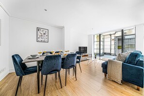 A modern living room with a dining area, a sofa, and a TV.