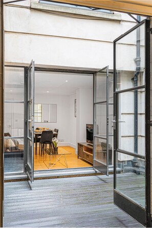 A modern interior with a dining area, a large open space, and a view through a glass door.