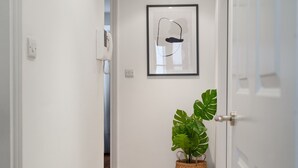 Ein Flur mit einer weißen Tür, einem gerahmten Kunstwerk und einem Blumentopf.