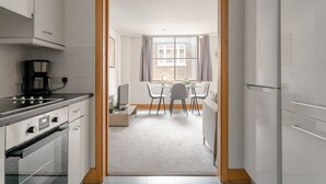 A modern kitchen with white cabinets, a stove, and a coffee maker. - Spacious 2-Bedroom Flat in London's Holborn (London)