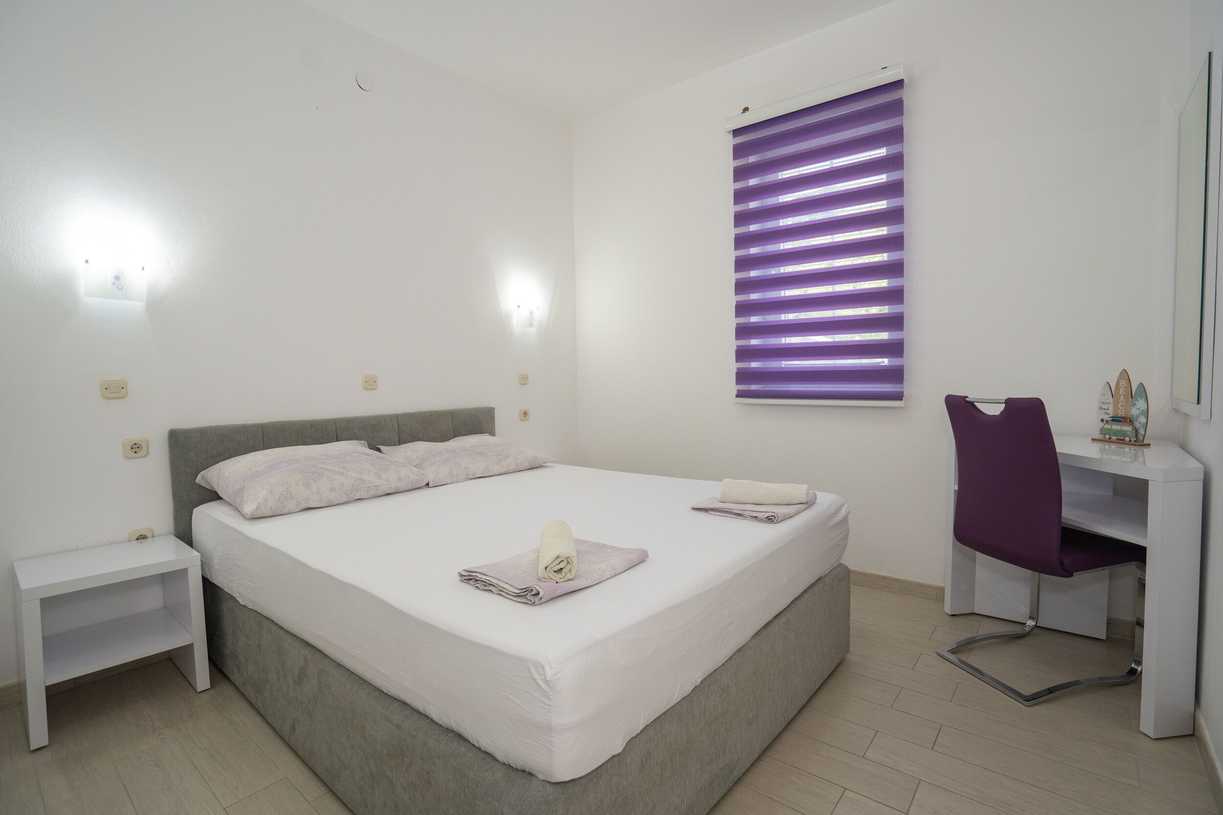 A bedroom with a bed, bedside tables, a desk, and a chair.