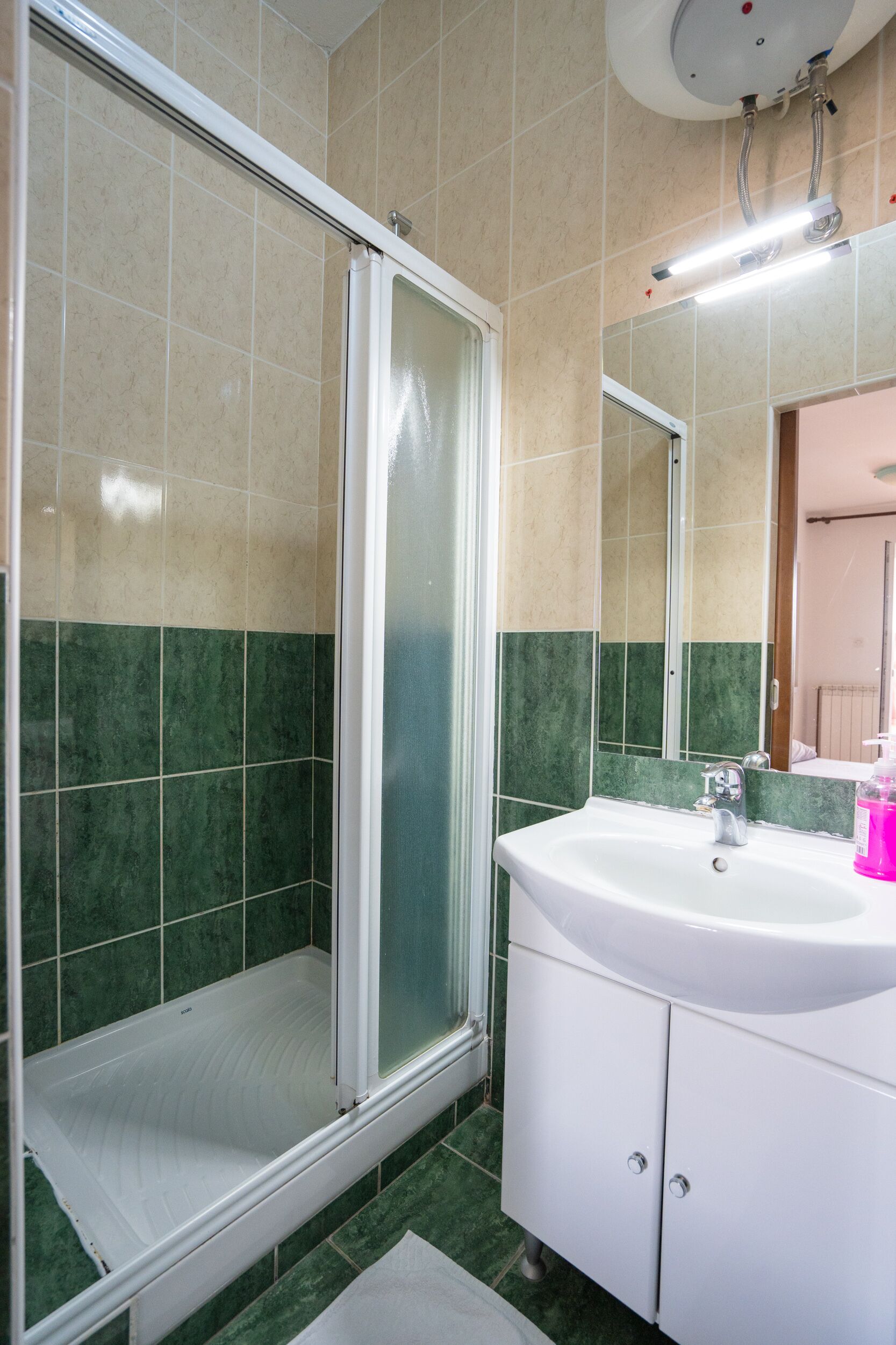 A bathroom with a glass-enclosed shower, a sink, and a mirror.