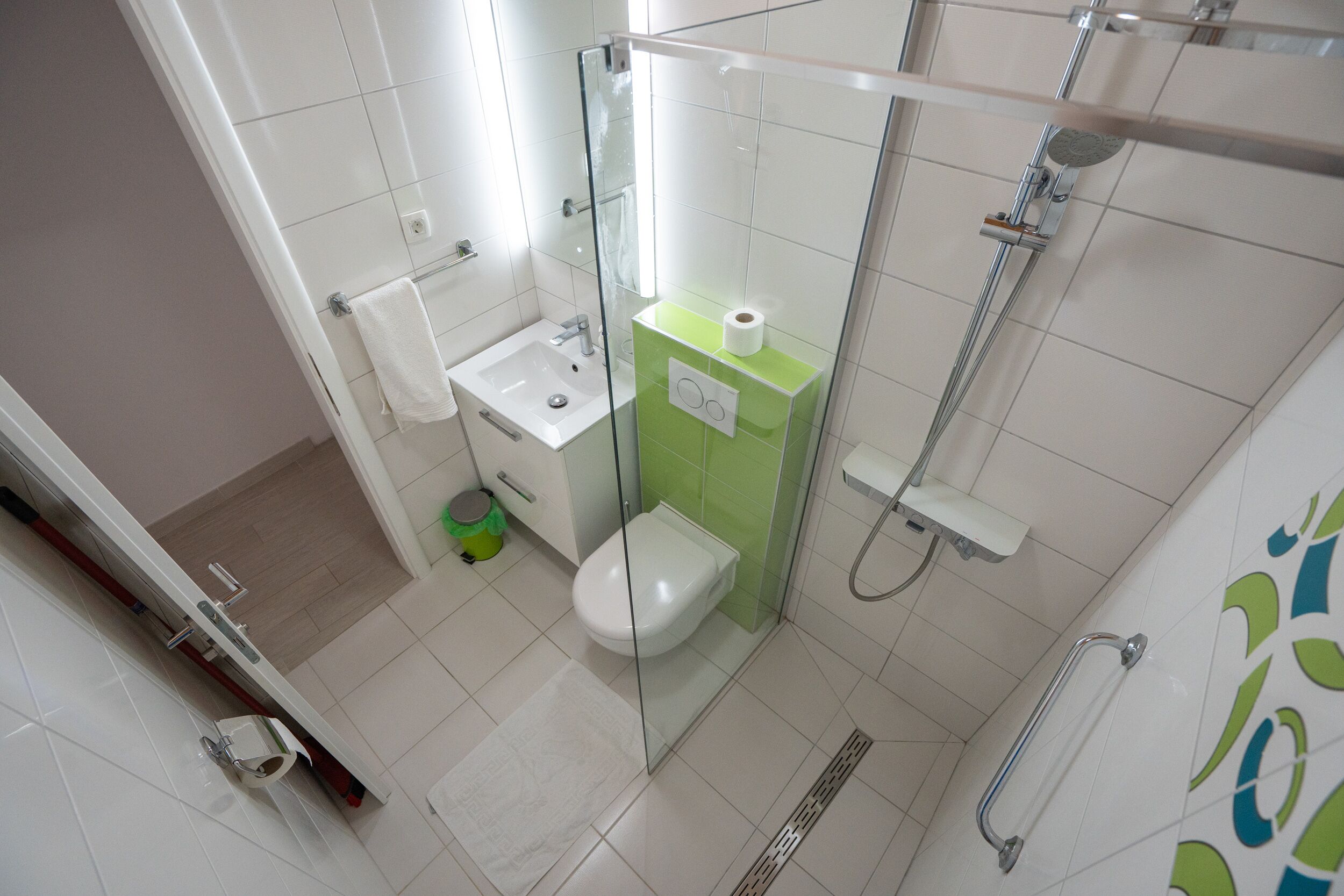 A modern bathroom with a glass-enclosed shower, a white sink, and a toilet.