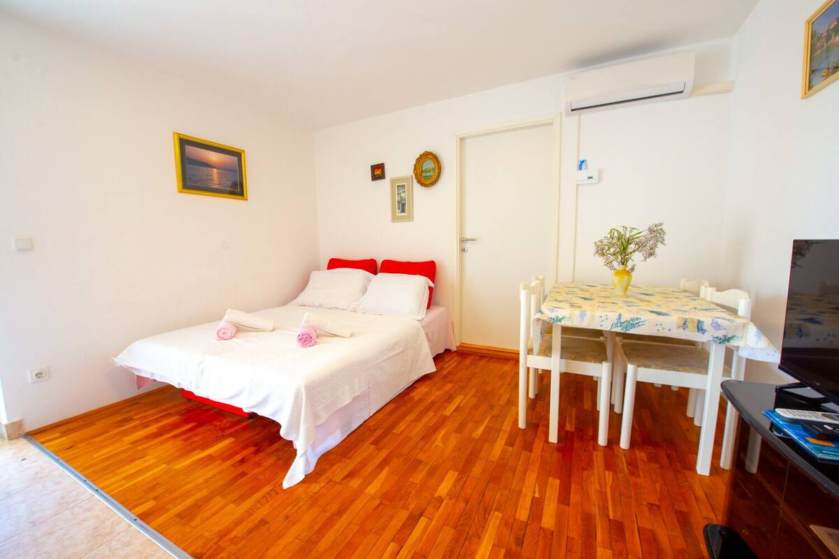 Une chambre à coucher comprenant un lit, une petite table avec des chaises, un bureau et un appareil de climatisation.