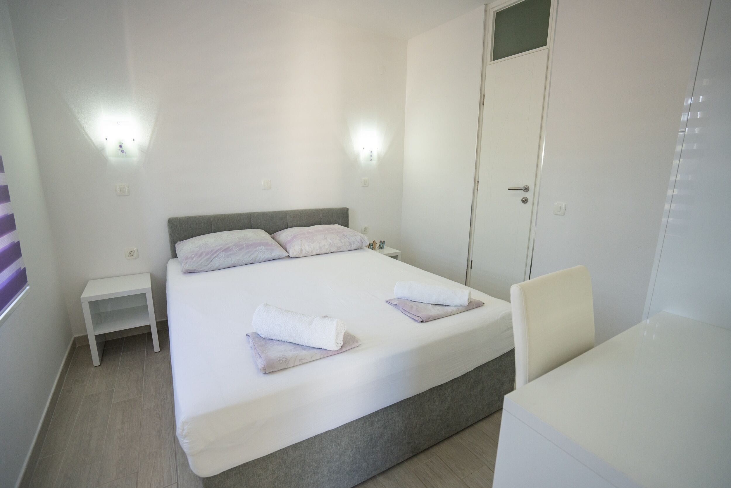 A bedroom with a bed, bedside tables, a wardrobe, and a chair.