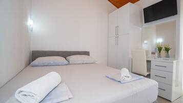 Un dormitorio moderno con cama, escritorio, silla y televisor montado en la pared.