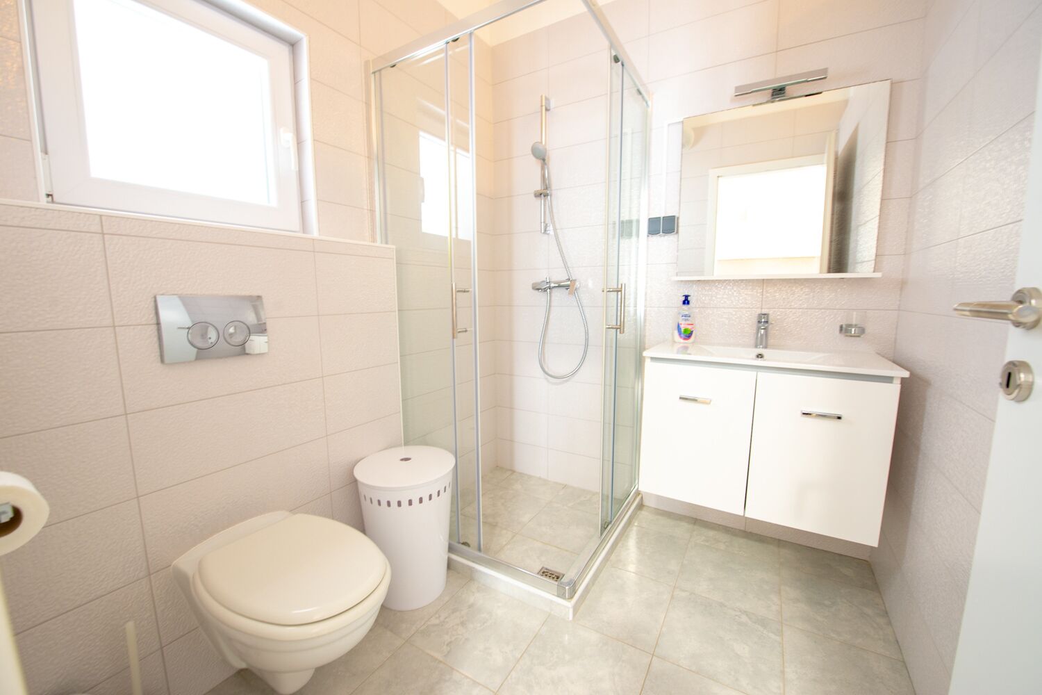 Un bagno moderno con doccia vetrata, un water e un lavandino con specchio sopra.