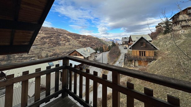 Une cabane en bois dotée d’un balcon donnant sur un paysage montagneux.
