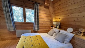 Et hyggeligt soveværelse i en træhytte med seng, puder, lampe og en bamse.