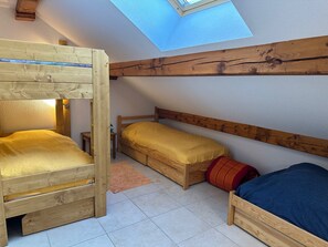 Three cozy beds with headboards and pillows are arranged in a row, under a skylight.