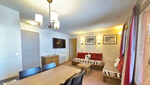 A cozy living room with a wooden dining table, two sofas, a TV, and a chandelier. - Bright ski-in/ski-out apartment with balcony in Vars Les Claux (Vars)