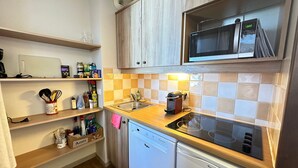 A compact kitchen with wooden cabinets, a microwave, a dishwasher, and a tiled backsplash. - Bright ski-in/ski-out apartment with balcony in Vars Les Claux (Vars)