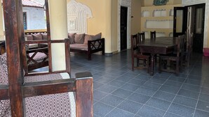 Un comedor amplio con una gran mesa de madera y sillas, un sofá con cojines estampados y paneles decorativos en la pared.
