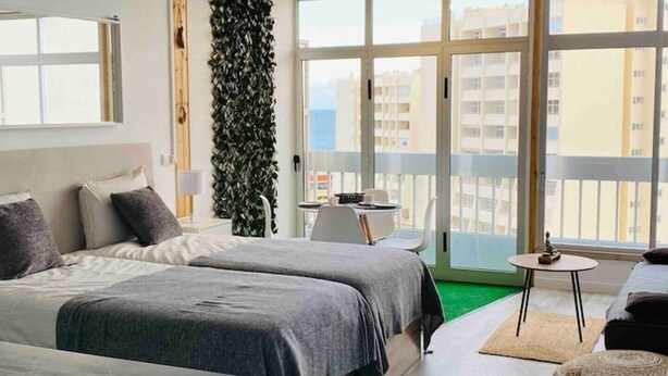 Habitación de hotel moderna con un balcón grande, una cama, un escritorio y una silla.