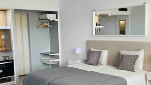 Un dormitorio moderno con cama, mesitas de noche, un espejo y un armario.