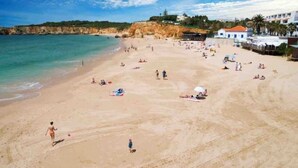 Una playa con gente tomando el sol y nadando. Se ven edificios al fondo.