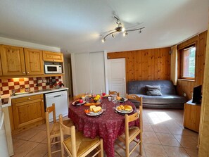 A compact kitchen with wooden cabinets, a microwave, and a dining area with a table set for a meal.