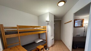 A compact dormitory room with bunk beds, a small wooden desk, a floor lamp, and a mirror on the wall. - Spacious T3 near slopes, south terrace, with WIFI, for 6 people (Vars)