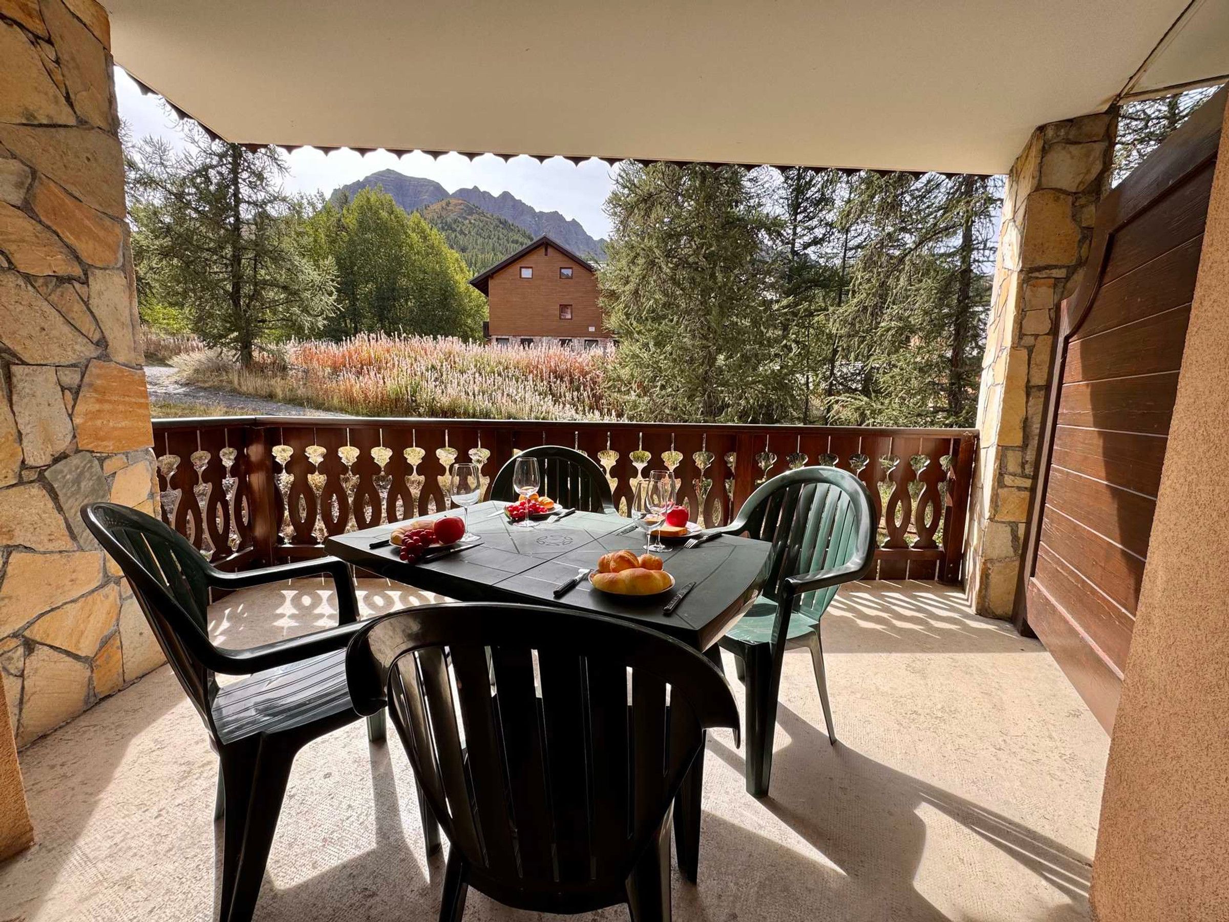 Un espace de restauration en plein air avec une table dressée pour quatre personnes, entouré de murs en pierre et offrant une vue sur une montagne.