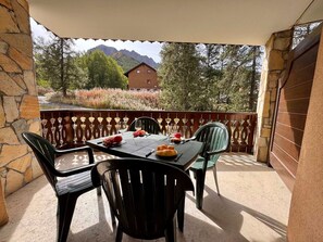 An outdoor dining area with a table set for four, surrounded by stone walls and a view of a mountain. - Spacious T3 near slopes, south terrace, with WIFI, for 6 people (Vars)