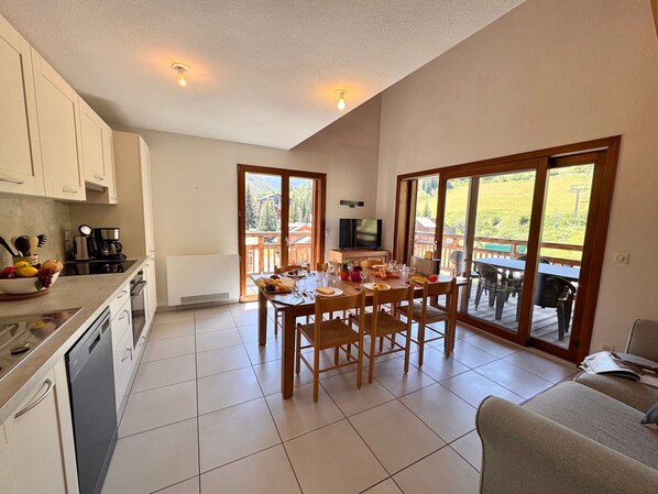 A modern kitchen with a dining area, a television, and a view of the outdoors.