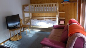 A room with a bunk bed, a television, a wooden chair, and a sofa. - 2-room apartment, terrace, pets allowed, Les Contamines-Montjoie (Les Contamines-Montjoie)