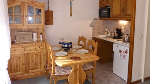 A compact kitchen with wooden cabinets, a dining table with chairs, and a small refrigerator. - 2-room apartment, terrace, pets allowed, Les Contamines-Montjoie (Les Contamines-Montjoie)