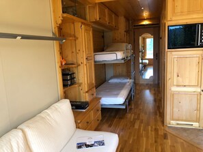 Une cabine compacte équipée de lits superposés, d’un coin cuisine et d’un petit espace salon.