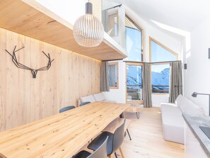 Enjoy expansive mountain views from the large windows in this stylish space, featuring a dining area with a long table and comfortable seating.