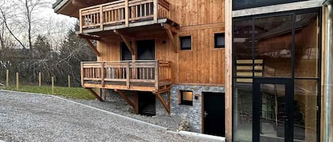 Eine Holzhütte mit Balkon, Steinunterbau und großen Fenstern.