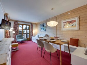 Una habitación acogedora con una pared de madera, una mesa de comedor con platos y vasos, un sofá y un televisor montado en la pared.
