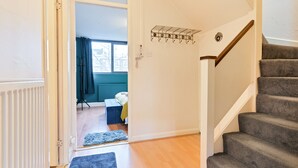 Un escalier menant à une chambre à coucher où se trouvent un lit, un tapis bleu et un porte-manteau.