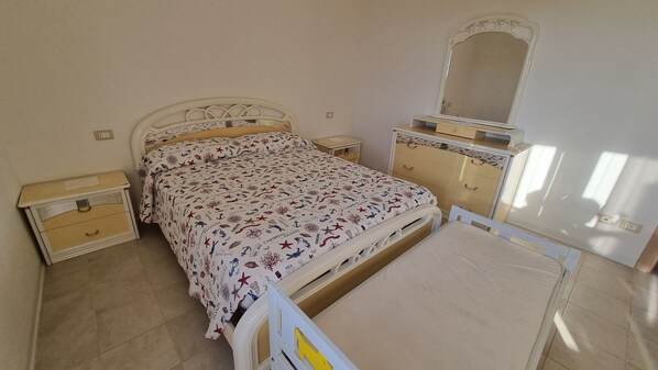 Un dormitorio con cama, cómoda, mesita de noche y espejo.