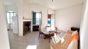 A spacious living area with a fireplace, a dining table with chairs, a sofa with cushions, and a kitchen in the background. - COTTAGE A FEW MINUTES FROM THE SEA (Fondi)
