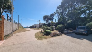 A paved pathway leading to a building with a fenced area and a parked car. - COTTAGE A FEW MINUTES FROM THE SEA (Fondi)
