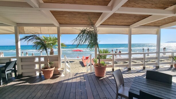 A covered outdoor area with wooden flooring, potted plants, and beach chairs. - COTTAGE A FEW MINUTES FROM THE SEA (Fondi)