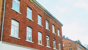 Un edificio de ladrillo rojo con varias ventanas y una puerta blanca.