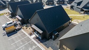 A row of modern cabins with sloped roofs, a parking lot, and a view of a large body of water. - Pet Friendly Home with Hot Tub Near Thunder Ridge & Table Rock Lake (Hollister)