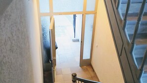Un escalier muni d’une rampe, menant à une porte ouverte en bas.