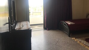 Una habitación con cama, cómoda y ventana con cortinas.