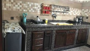 Una cocina con encimeras de granito, armarios de madera oscura, una estufa a gas y una cafetera.