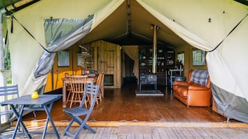 A tented accommodation with a dining area, a sofa, and a kitchen area.