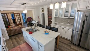 Een moderne keuken met witte kasten, een roestvrijstalen koelkast en een centraal eiland met een spoelbak en een blauwe kom.