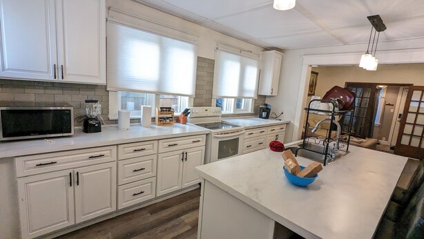 Een moderne keuken met witte kastjes, een ingebouwde oven, een magnetron en een koffiezetapparaat.