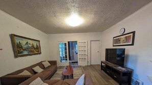 Een woonkamer met een bruine bank, een salontafel, een tv-meubel en een schilderij aan de muur.